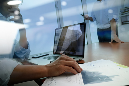 business documents on office table with smart phone and digital tablet and graph business diagram and man working in the background